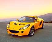 AUT 04 RK0120 01
2003 Lotus Elise Yellow 3/4 Front View On Pavement Hill Mountains Background