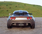 AUT 04 RK0144 02
2006 Lotus Exige Silver 3/4 Rear View On Pavement By Grass Hills Blue Sky
