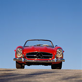 AUT 05 RK0145 01
Mercedes Benz 300SL Convertible Red Low Head On Shot On Pavement Blue Sky