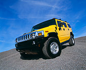 AUT 15 RK0621 02
2003 Hummer H2 Yellow 3/4 Front Low View Wide Angle Shot On Gravel Blue Sky