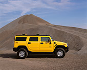 AUT 15 RK0623 05
2003 Hummer Yellow H2 Profile View By Pile Of Gravel Blue Sky