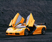 AUT 28 RK0015 04
1996 McLaren F1 LM Orange 3/4 Front View Doors Open Lights On In Coal Field