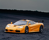 AUT 28 RK0045 04
1996 McLaren F1 LM Orange Front 3/4 View On Black Coal Field Headlights On