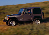 AUT 29 RK0702 01
2004 Jeep Wrangler Rubicon Light Khaki 3/4 Side View On Hill In Motion