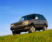 AUT 33 RK0131 02
2000 Range Rover Gold 3/4 Slanted 3/4 Front View On Grass Hill Blue Sky