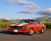 CAM 03 RK0036 03
1969 Chevrolet Camaro RS-Z28 Hugger Orange White Stripe Front 3/4 View On Pavement By Yellow Flowers