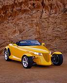 AUT 03 RK0015 06
1999 Plymouth Prowler Roadster Yellow 3/4 Front View On Sand Against Rock