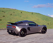 AUT 04 RK0142 02
2006 Lotus Exige Silver 3/4 Rear View On Pavement By Grass Hills Blue Sky