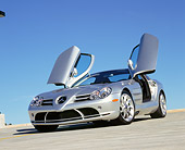 AUT 05 RK0429 03
2005 Mercedes-Benz SLR McLaren Silver Low 3/4 Front View Butterfly Doors On Pavement Blue Sky