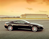 AUT 06 RK0060 02
2005 Aston Martin DB9 Coupe Black Profile On Pavement By Airplane Hanger Filtered