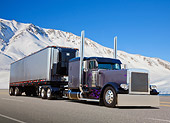 AUT 07 RK0282 01
2002 Peterbilt 379 Gray With Black Fenders And Trailer 3/4 Front View On Road By Snow Covered Hills