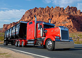 AUT 07 RK0386 01
1995 Kenworth W900 Red With Black Trailer 3/4 Front View On Road By Red Rock
