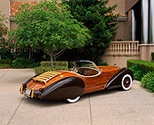AUT 09 RK0402 04
The Dolphin Wooden Roadster Rear 3/4 View On Pavement By Building And Trees