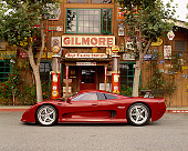 AUT 09 RK0654 02
2003 Mosler MT900S Prototype Rosa Barchetta Profile View On Pavement By Building