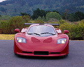 AUT 09 RK0661 03
2003 Mosler MT900S Prototype Rosa Barchetta Head On View On Pavement By Shrubs Hills