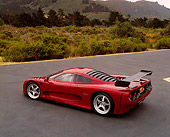 AUT 09 RK0668 04
2003 Mosler MT900S Prototype Rosa Barchetta Rear 3/4 View On Pavement By Bushes