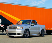 AUT 09 RK0675 04
Ford F-150 Lightning Concept Truck Silver 3/4 Side View On Pavement By Orange Semi Truck