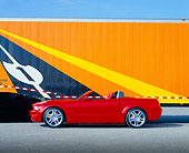 AUT 09 RK0682 03
Ford Mustang GT Convertible Red Side View On Pavement By Orange Semi Truck