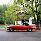 AUT 12 RK0018 02
1964 Red Jaguar XKE Conv Side View In Front House By Trees