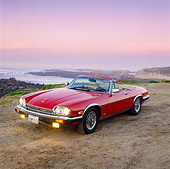 AUT 12 RK0038 09
1988 Red Jaguar XJ5 Conv 3/4 Front View On Dirt Road Headlights On At Dusk