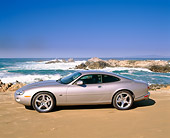AUT 12 RK0121 02
2001 Jaguar XKR Silverstone Coupe Side View On Sand By Ocean And Rocks Blue Sky