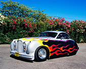 AUT 12 RK0202 02
1952 Jaguar Mark VII Silver With Flames 3/4 Front View On Pavement By Flowering Shrubs