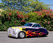AUT 12 RK0205 04
1952 Jaguar MK VII Silver With Flames 3/4 Side View On Pavement By Pink Bushes