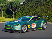 AUT 13 RK0270 01
2007 Aston Martin DBR9 Race Car 007 Green 3/4 Front View On Pavement By Shrubs