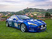 AUT 13 RK0356 01
2010 Aston Martin Rapide Race Car Blue 3/4 Front View On Grass By Hills