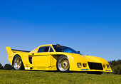 AUT 13 RK0205 01
1977 De Tomaso Pantera Class C Yellow Front 3/4 View Low Angle On Grass Blue Sky