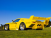 AUT 13 RK0209 01
1977 De Tomaso Pantera Class C Yellow Rear 3/4 View Low Angle On Grass Blue Sky