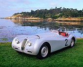 AUT 13 RK0268 01
Jaguar XK120 Competition Roadster Silver 3/4 Front View On Grass By Ocean