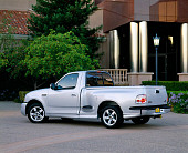 AUT 14 RK0632 01
2001 Ford Lightning F-150 Silver 3/4 Rear View On Pavement By Building And Trees