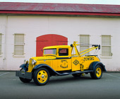AUT 14 RK0972 03
1934 Ford Tow Truck Yellow And Blue 3/4 Side View On Pavement By Building