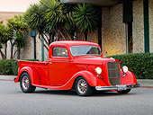 AUT 14 RK1422 01
1935 Ford Pickup Truck Red 3/4 Front View On Pavement By Building And Trees