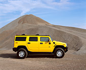 AUT 15 RK0623 05
2003 Hummer Yellow H2 Profile View By Pile Of Gravel Blue Sky