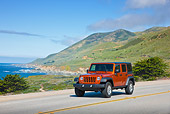 AUT 15 RK1227 01
2011 Jeep Wrangler Rubicon Orange 3/4 Front View On Road By Beach And Hills