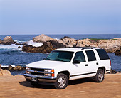AUT 15 RK0186 08
1999 Chevrolet Tahoe White Front 3/4 Front View On Sand By Ocean And Rocks