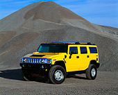 AUT 15 RK0612 02
2003 Hummer H2 Yellow 3/4 Front View By Pile Of Gravel Blue Sky