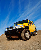 AUT 15 RK0621 05
2003 Hummer H2 Yellow 3/4 Front Low View Wide Angle Shot On Gravel Blue Sky