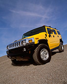 AUT 15 RK0621 22
2003 Hummer H2 Yellow 3/4 Front Low View Wide Angle Shot On Gravel Blue Sky