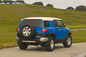 AUT 15 RK0968 01
2007 Toyota FJ Cruiser Blue And White Slanted 3/4 Rear View On Pavement By Grass Hills