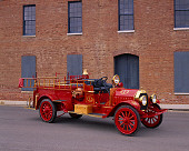 AUT 16 RK0134 01
1909 Kissel Hose And Chemical Fire Truck Red 3/4 Front View On Pavement By Building