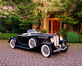 AUT 19 RK0505 08
1933 Auburn V12 Boat-Tail Speedster Black 3/4 Side View On Pavement By Trees And Bushes