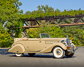 AUT 19 RK1019 01
1935 Hudson Convertible Pepper Tan 3/4 Side View On Pavement By Gate And Trees
