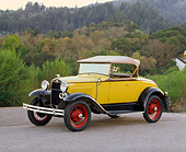 AUT 19 RK0384 01
1931 Ford Model A Deluxe Roadster Yellow 3/4 Front View On Pavement By Trees And Bushes