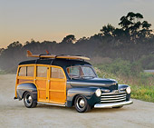 AUT 20 RK0014 04
1946 Ford Woodie Green With Surfboard 3/4 Side View On Road By Trees