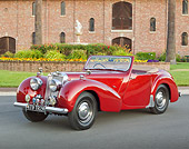 AUT 20 RK0576 01
1949 Triumph 2000 Roadster Red 3/4 Front View On Pavement By Brick Building