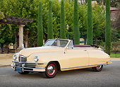 AUT 20 RK0650 01
1948 Packard Super 8 Convertible Arizona Beige 3/4 Front View On Pavement By Shrubs