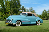 AUT 20 RK0659 01
1947 Oldsmobile Series 68 Convertible Caspian Blue 3/4 Side View On Grass By Trees